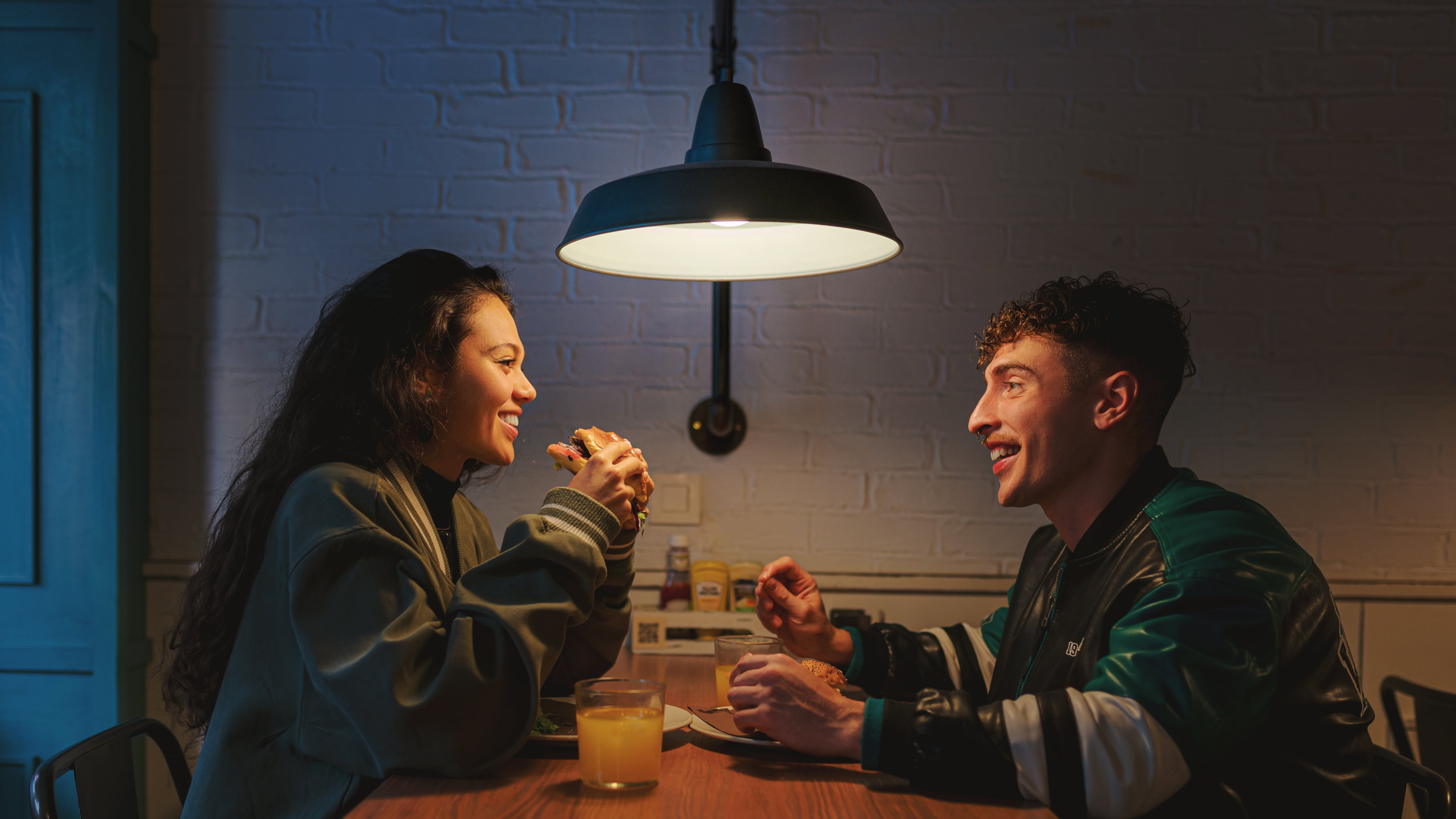 Feliz pareja disfrutando de hamburguesas y bebidas en una cita nocturna en el restaurante