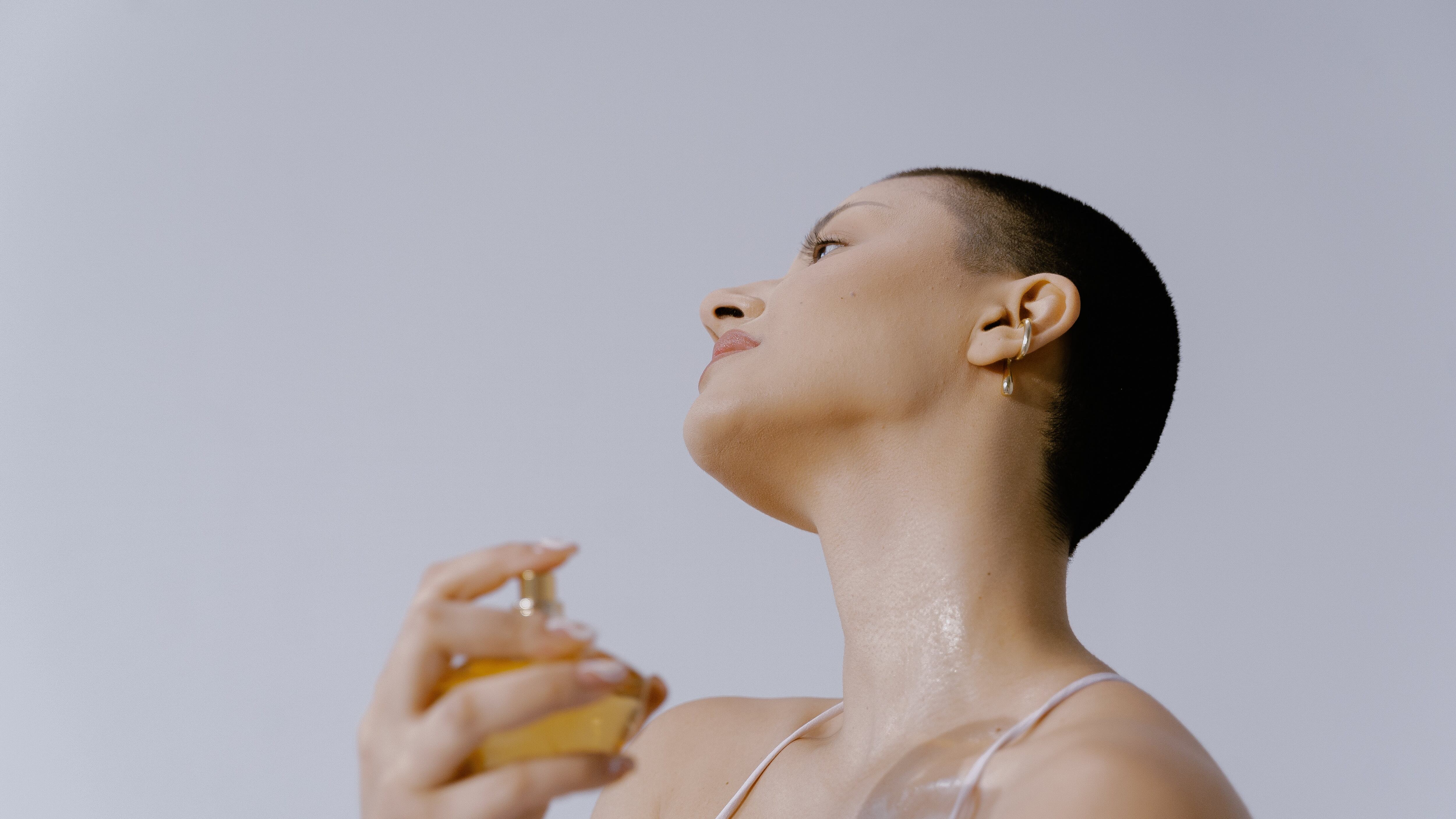 Mulher careca espirrando perfume no pescoço