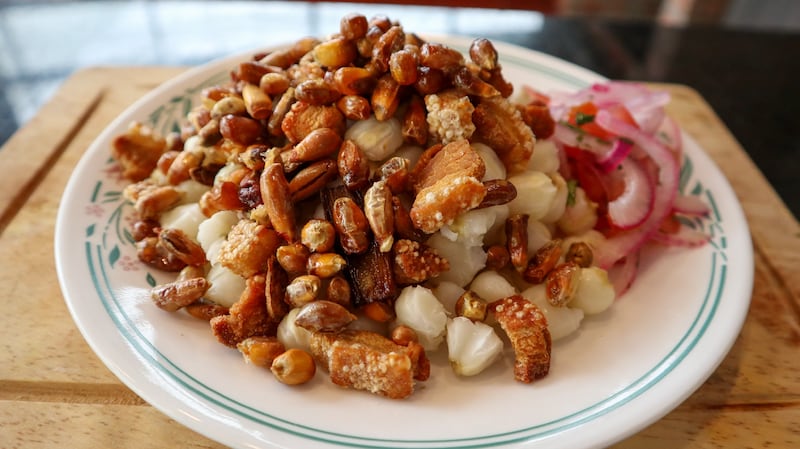 Maíz blanco cocido acompañado de chicharrón y ají, un desayuno contundente y lleno de sabor.
