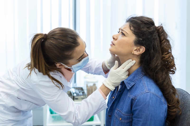 Mulher com dor na garganta sendo consultada por médica