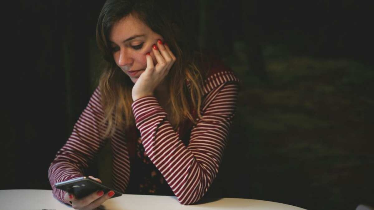 Una mujer con una expresión de decepción mientras mira su teléfono